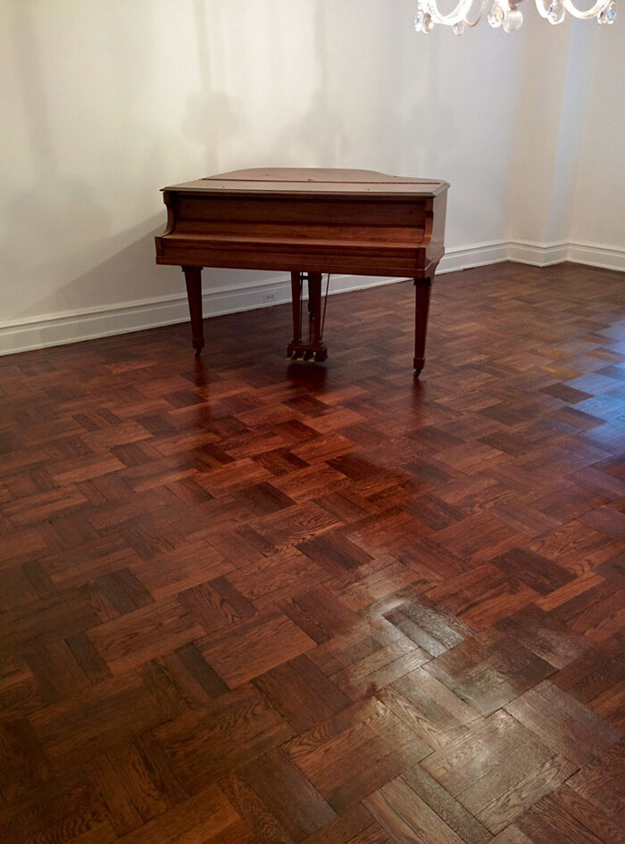 Restored dark parquet floor in a residence with a grand piano
