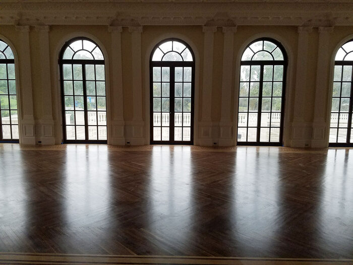 Refinished hardwood floor in a ballroom with arched windows